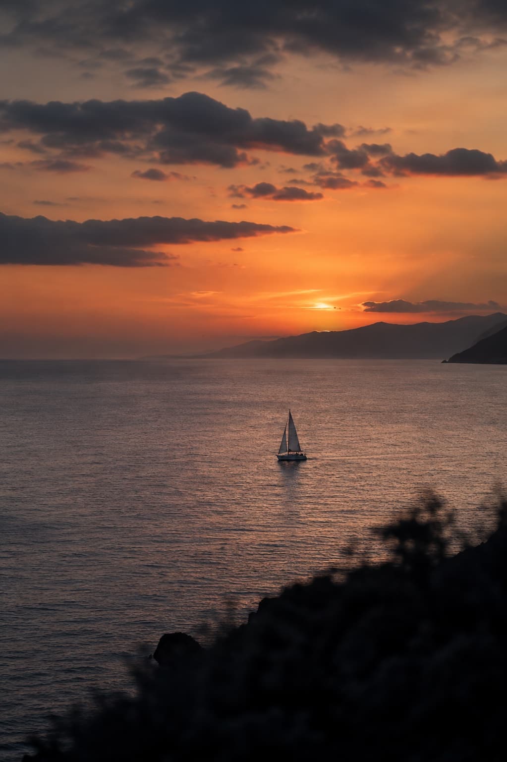 A sailboat off the coast at sunset